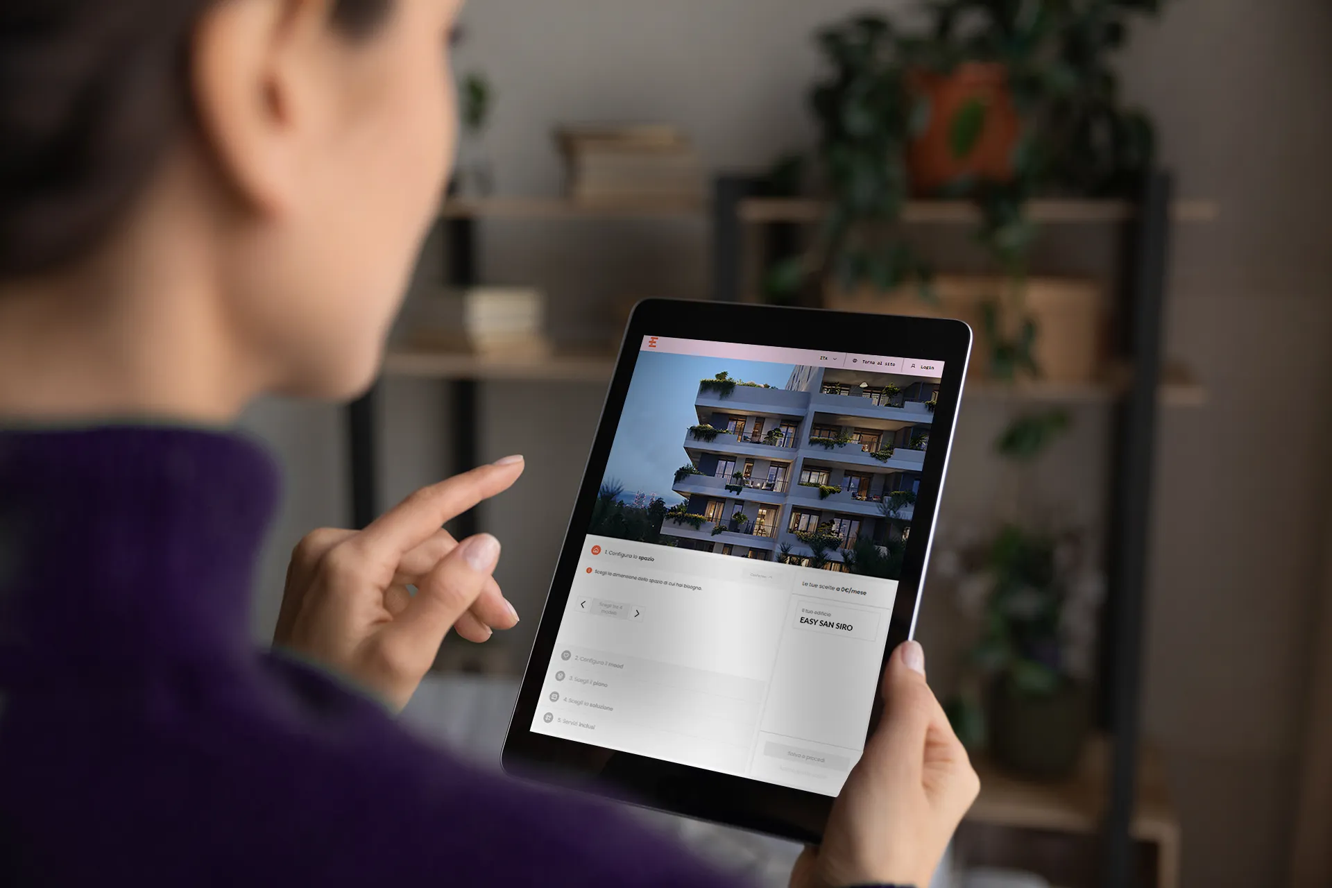 Persona che usa un tablet con l’immagine di un edificio residenziale sullo schermo.